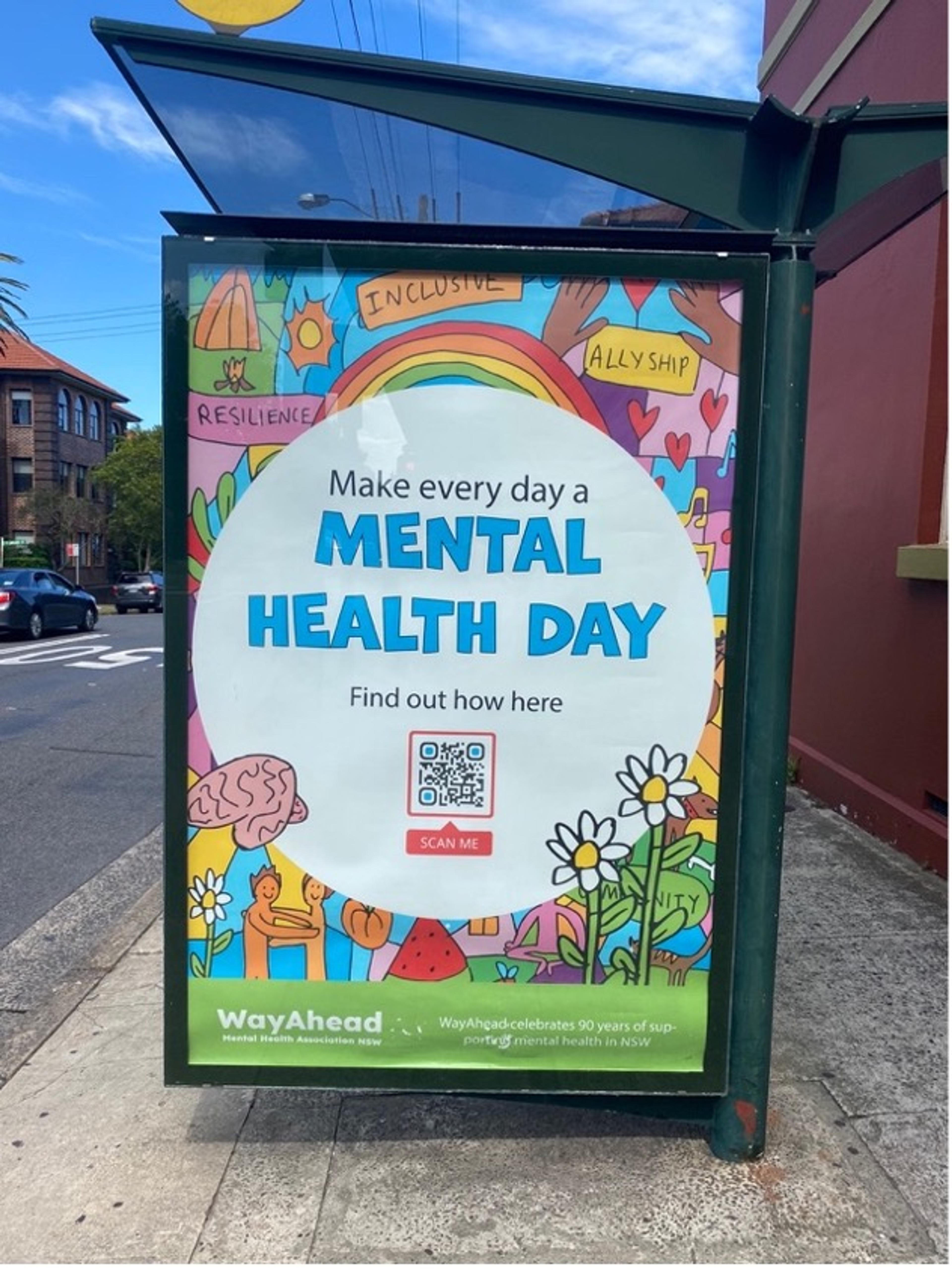 Photo of a colourful poster at a bus stop promoting mental health awareness with a QR code for more information.