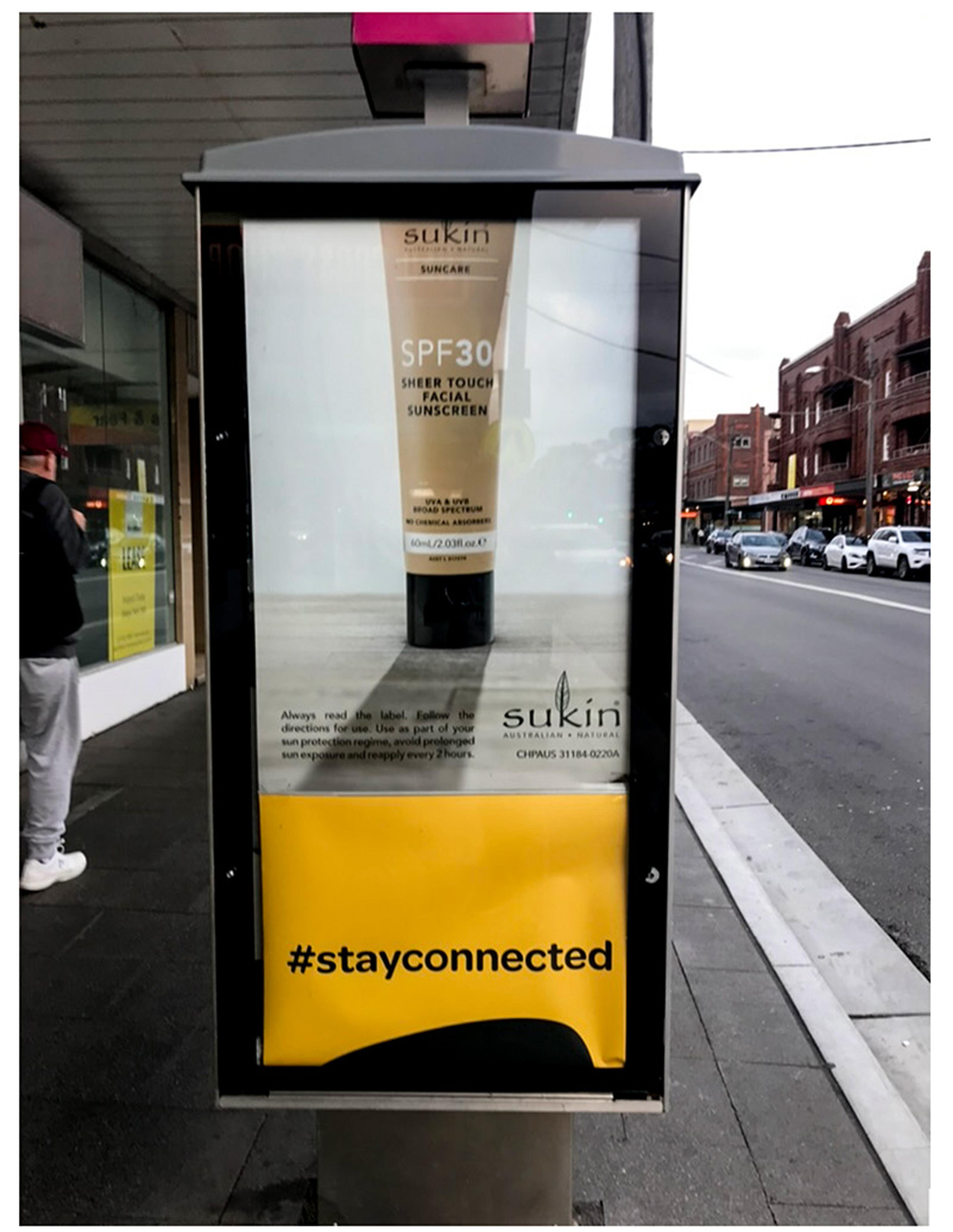 Photo of a street ad for Sukin SPF 30 sunscreen changing to an ad for the charity R U OK? and the hashtag #stayconnected.