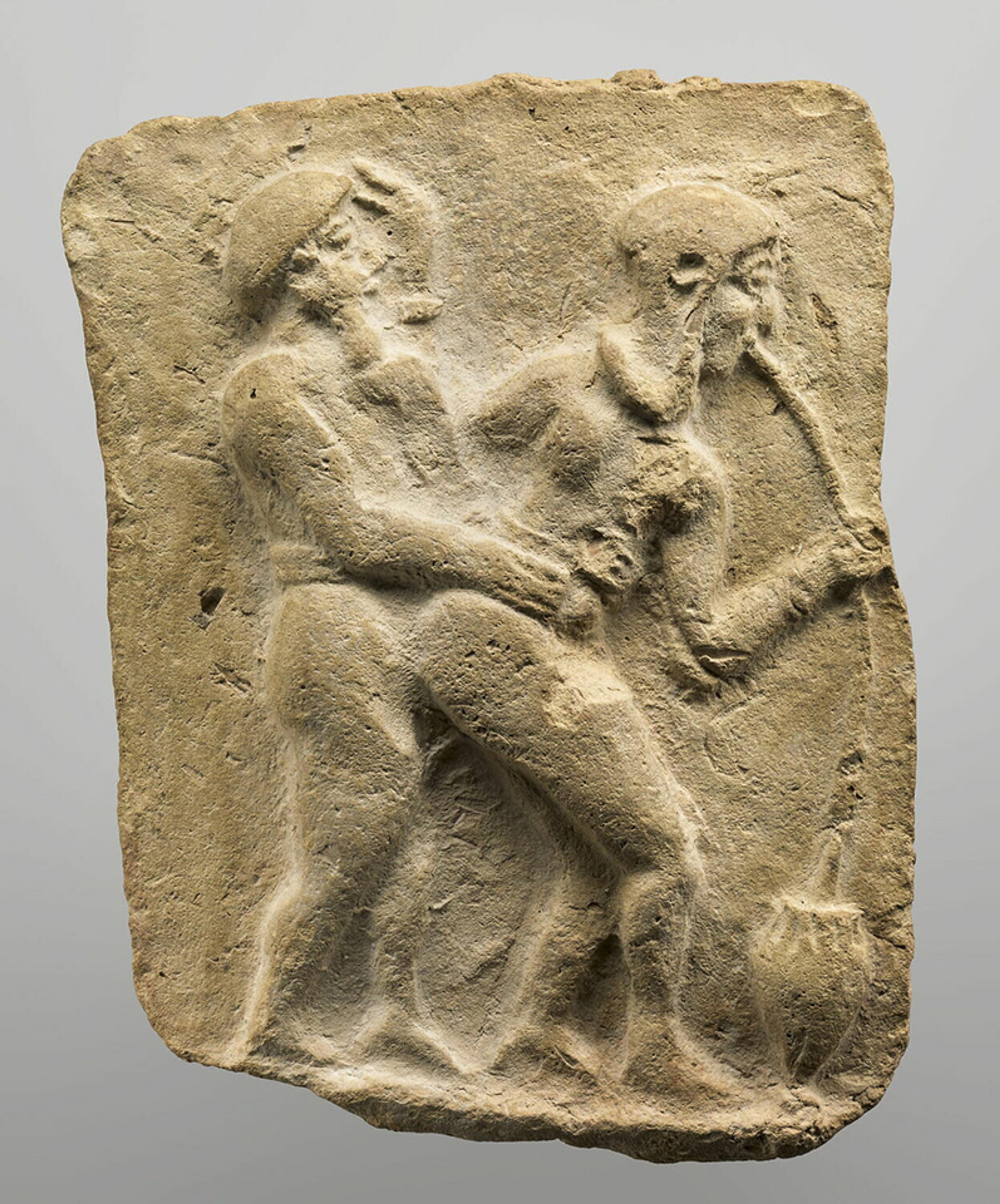 Ancient clay plaque depicting two figures, one male and one female, in a suggestive embrace, the female drinking from a straw.