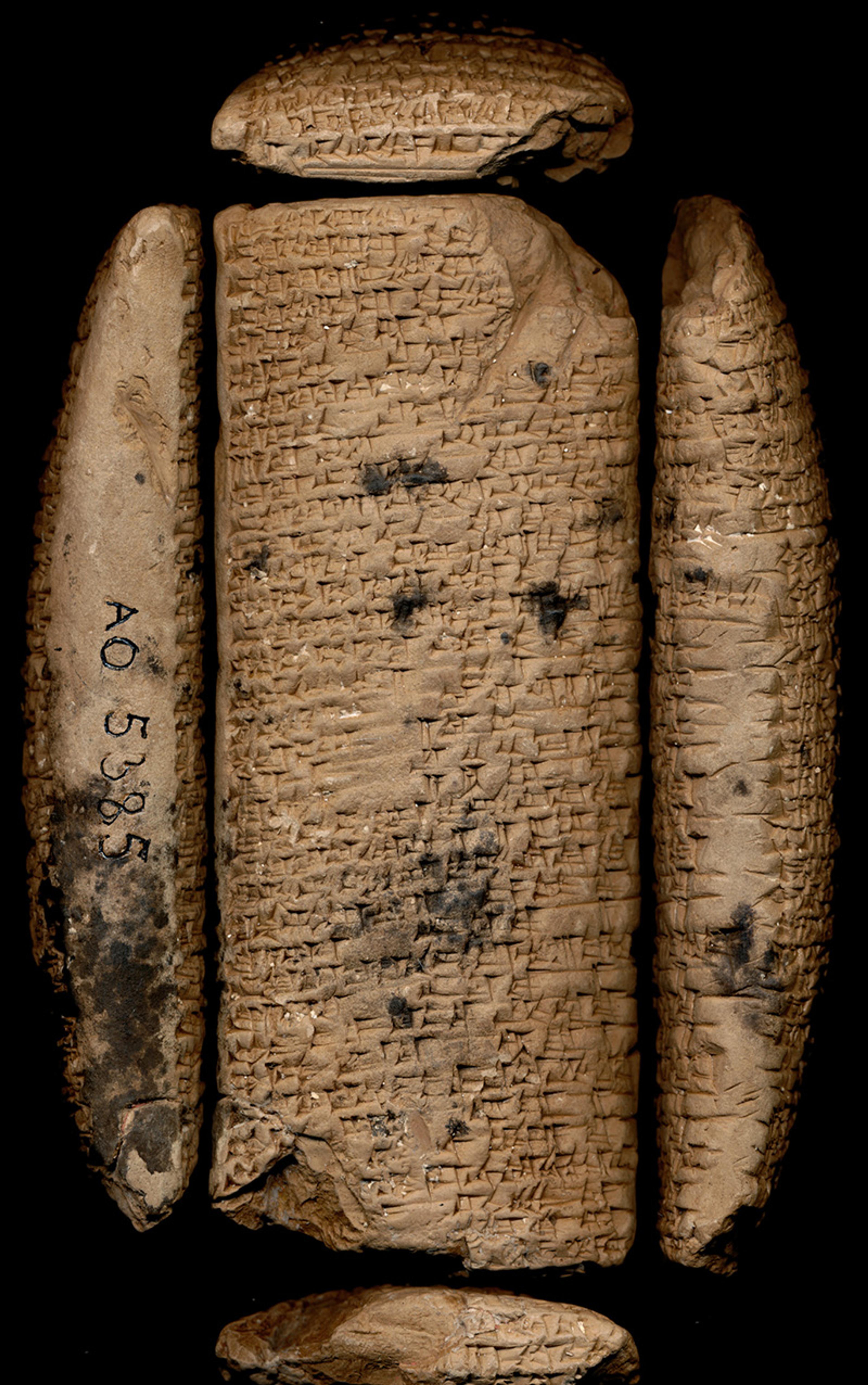 An ancient clay tablet with cuneiform script, surrounded by other fragments on a black background.