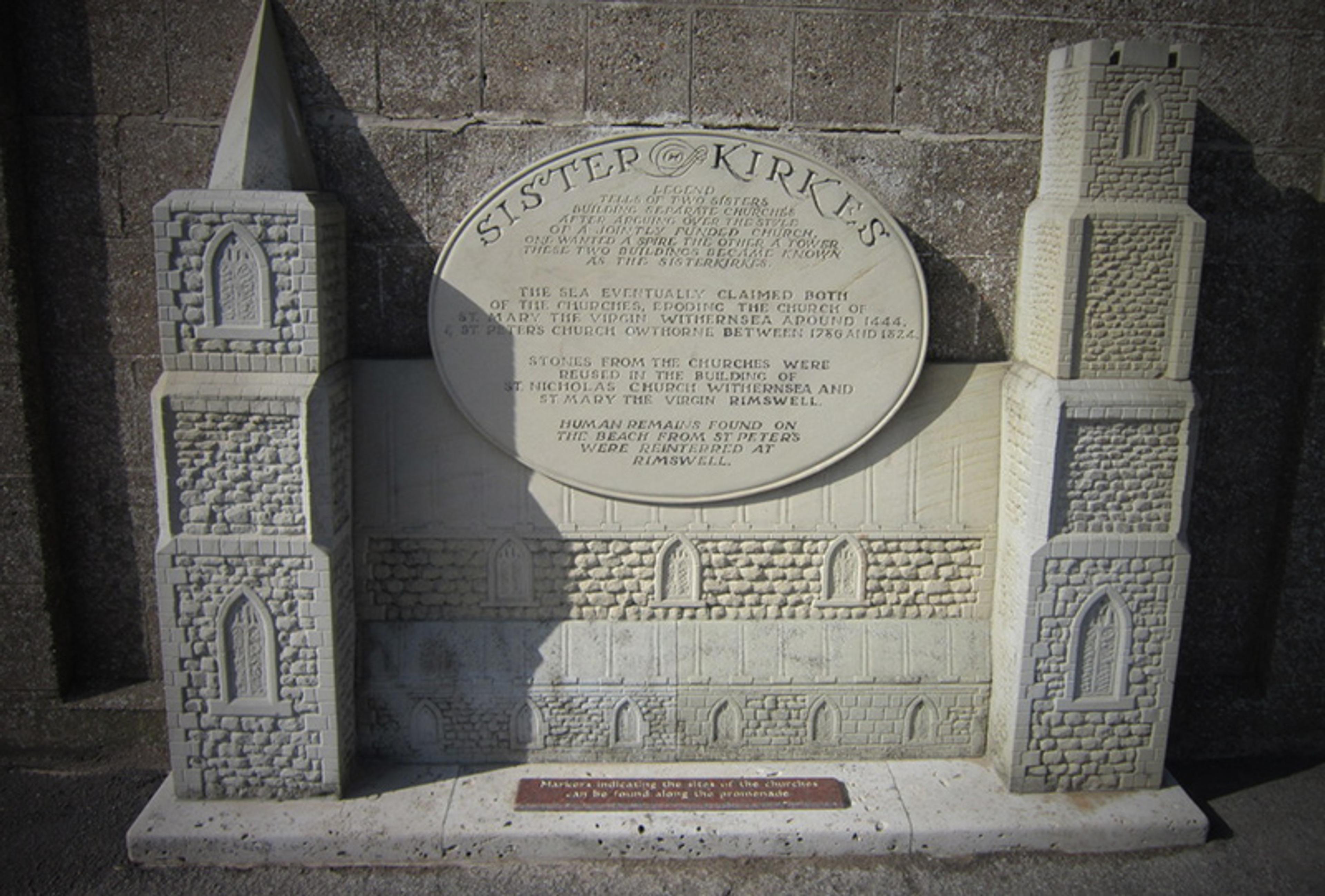 Stone relief sculpture depicting Sister Churches with historical inscription.