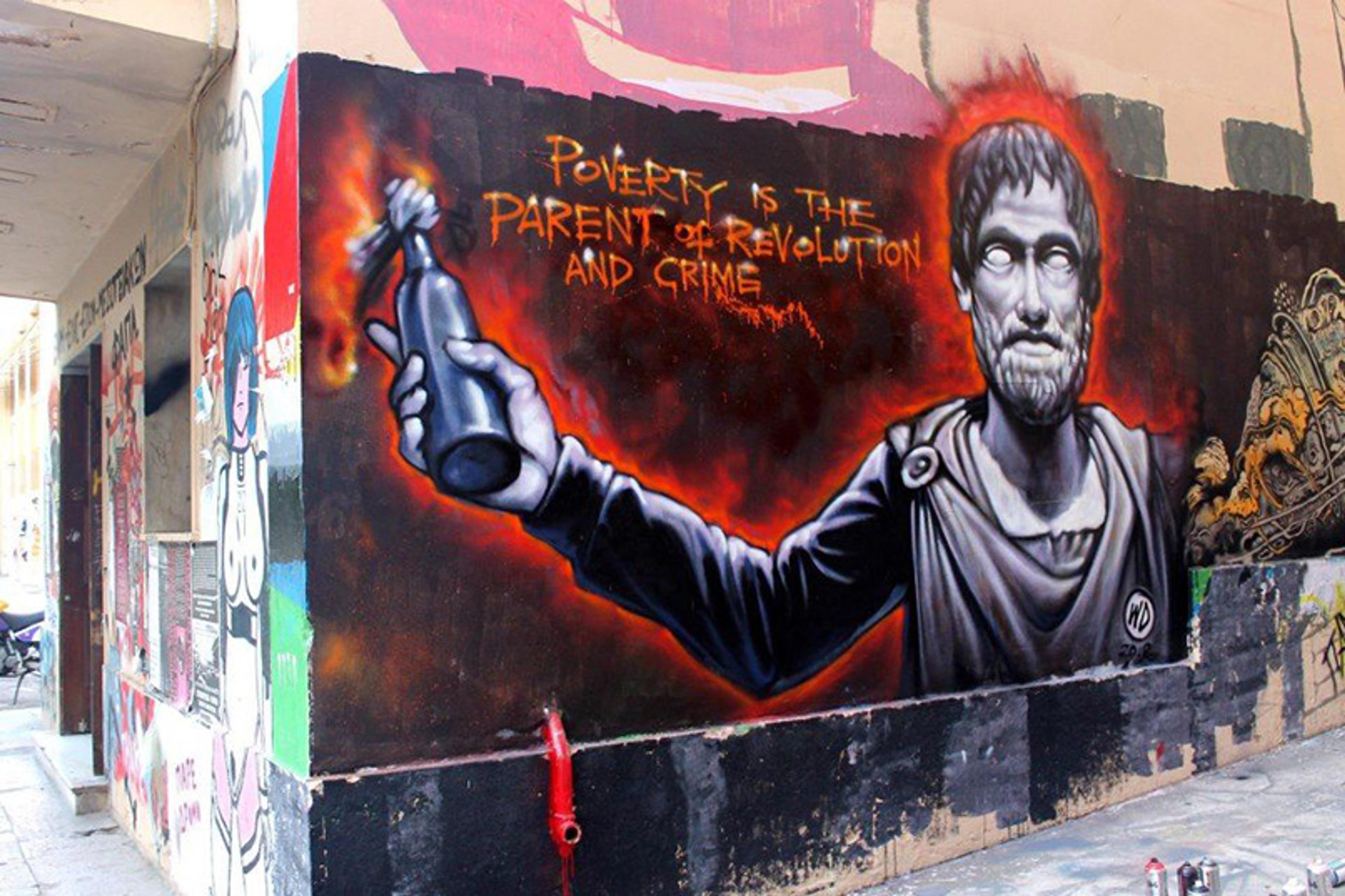 Graffiti on a wall shows a statue-like figure holding a Molotov cocktail with text: “Poverty is the parent of revolution and crime.”