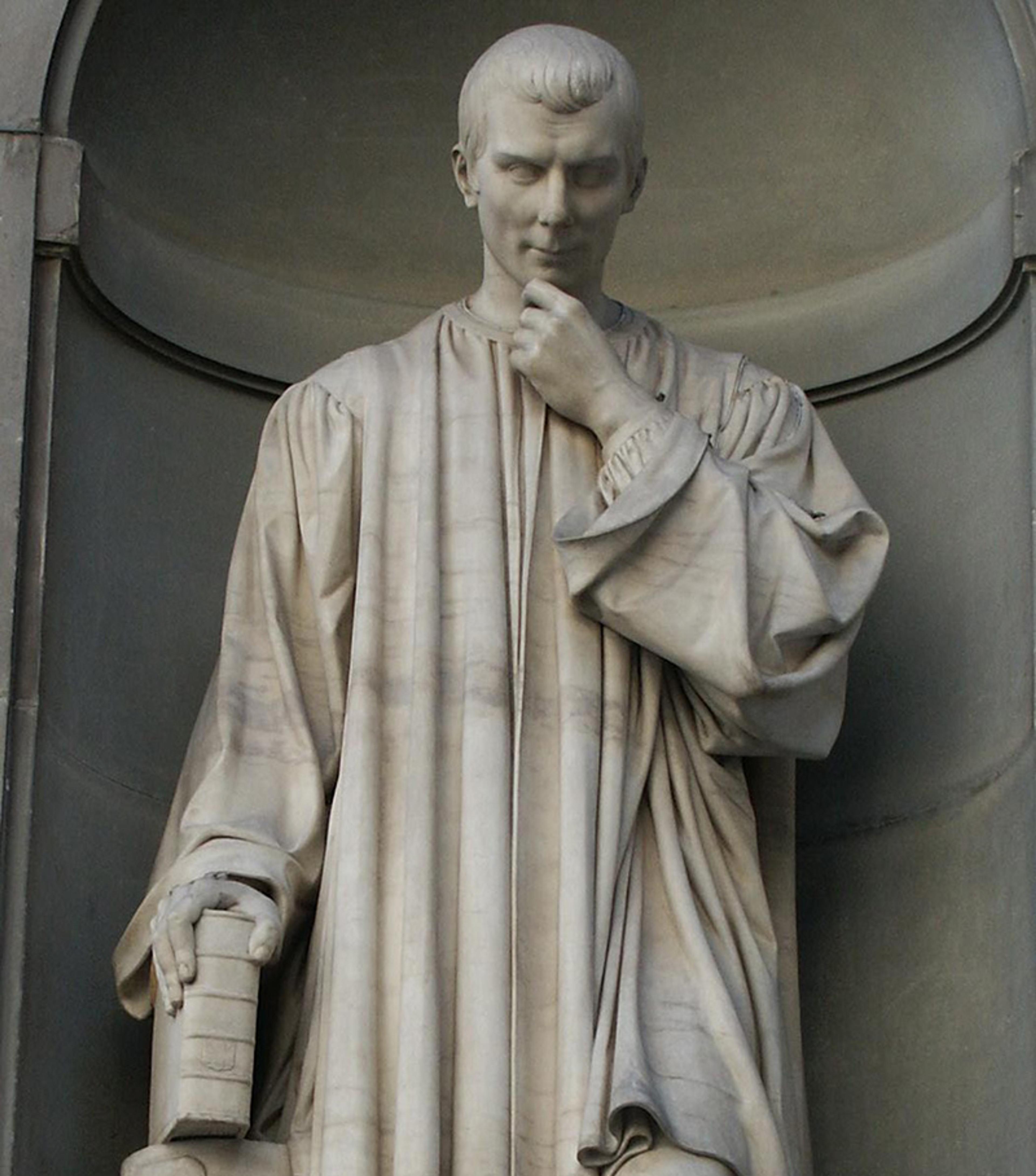 Marble statue of a man in thought, holding a book, wearing a robe in a niche.