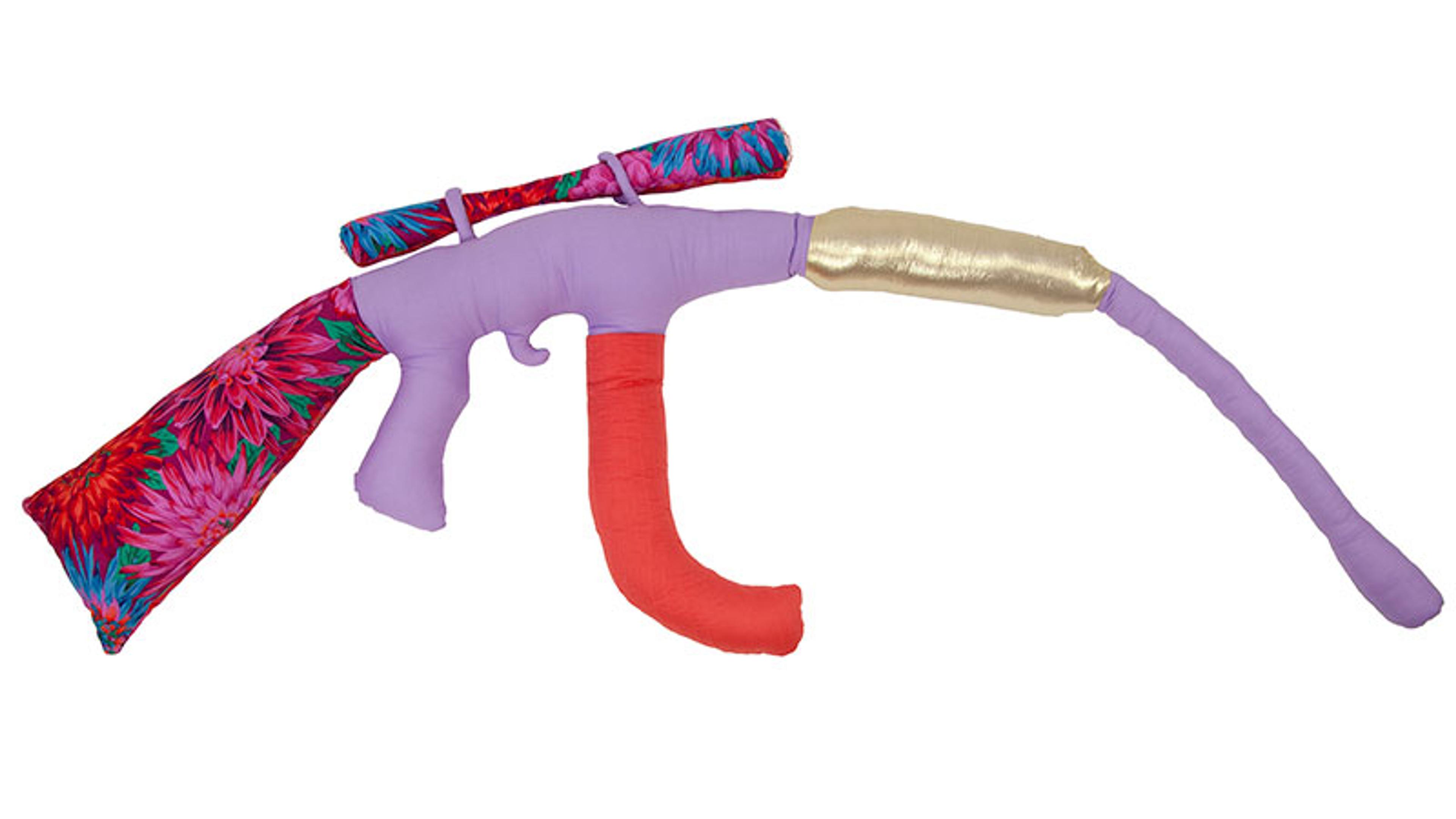 Colourful textile sculpture shaped like a rifle, featuring a mix of red, purple, gold and floral patterns.