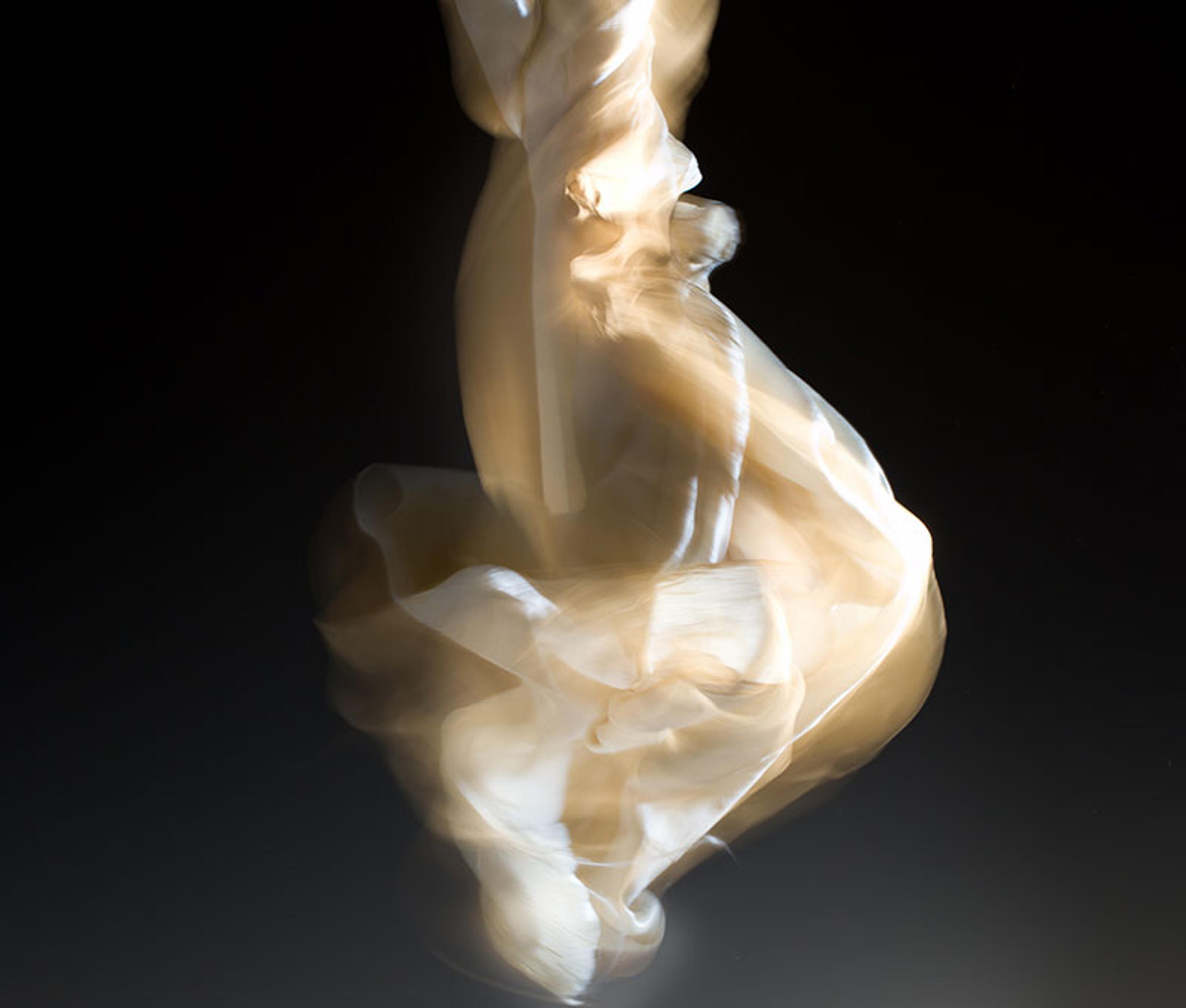 Abstract photo of swirling beige smoke or liquid against a dark background, creating a sense of motion and fluidity.