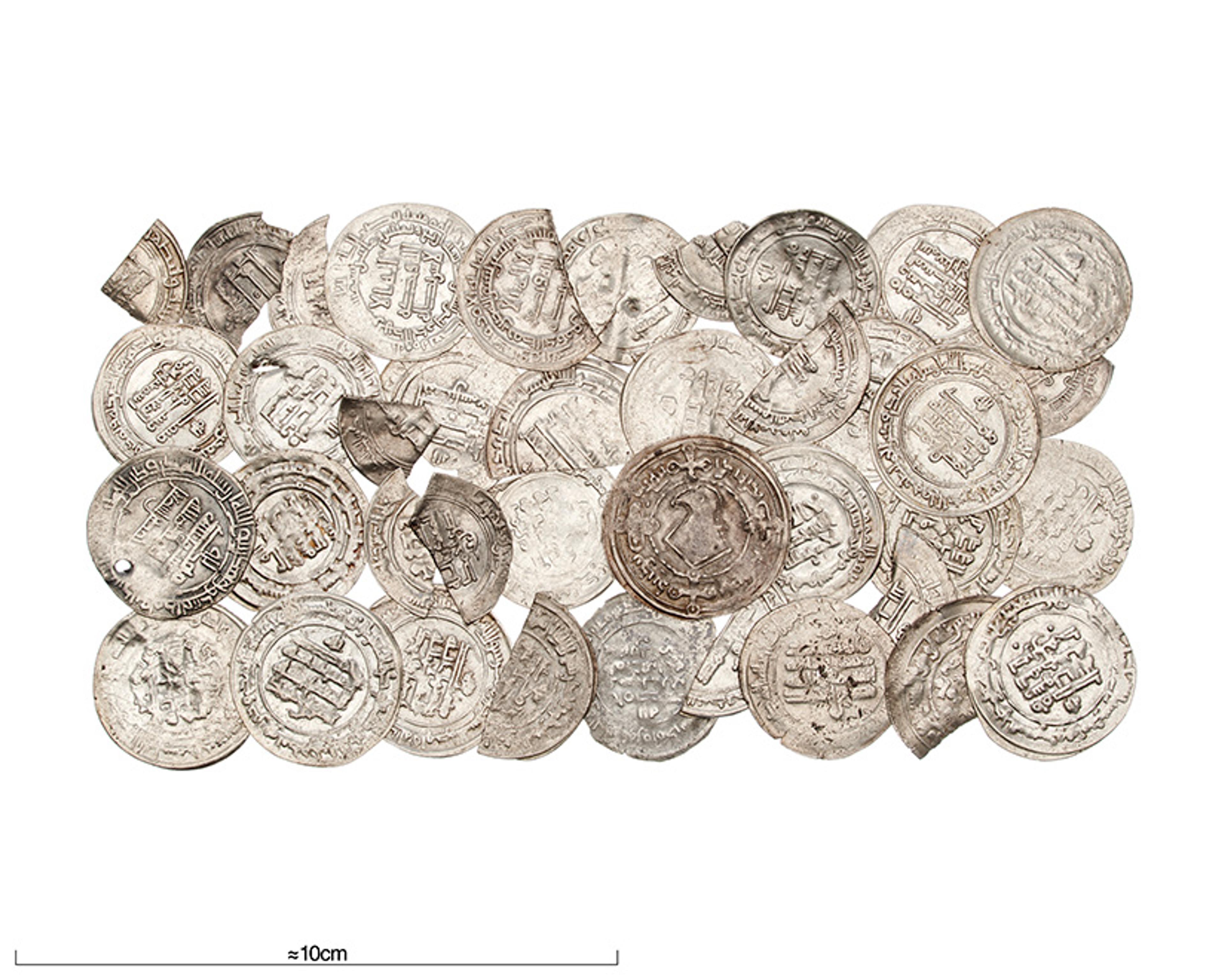A collection of ancient silver coins with inscriptions stacked together, with a 10cm scale at the bottom.