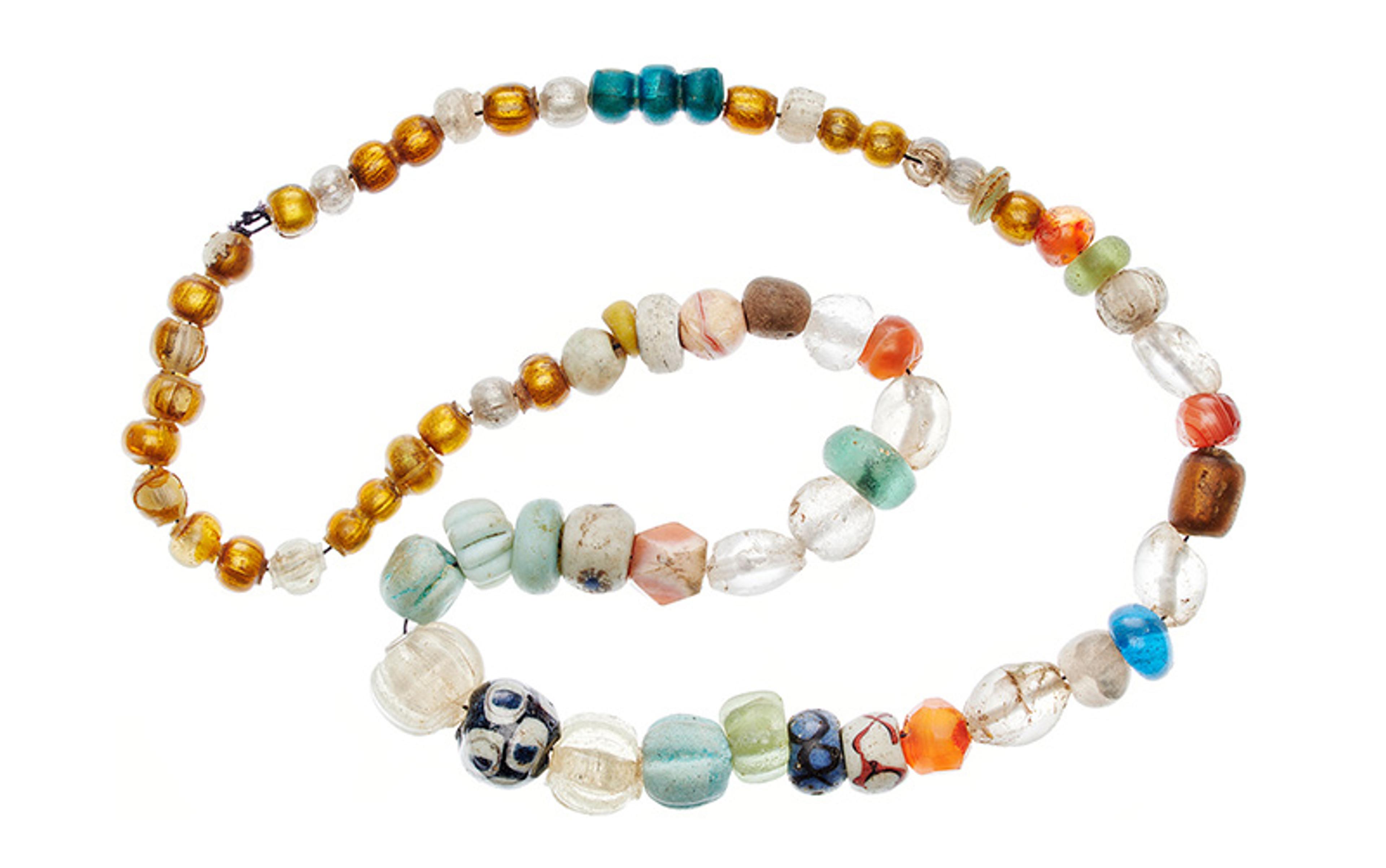 A multicoloured beaded necklace arranged in a spiral on a white background displaying various shapes and patterns.