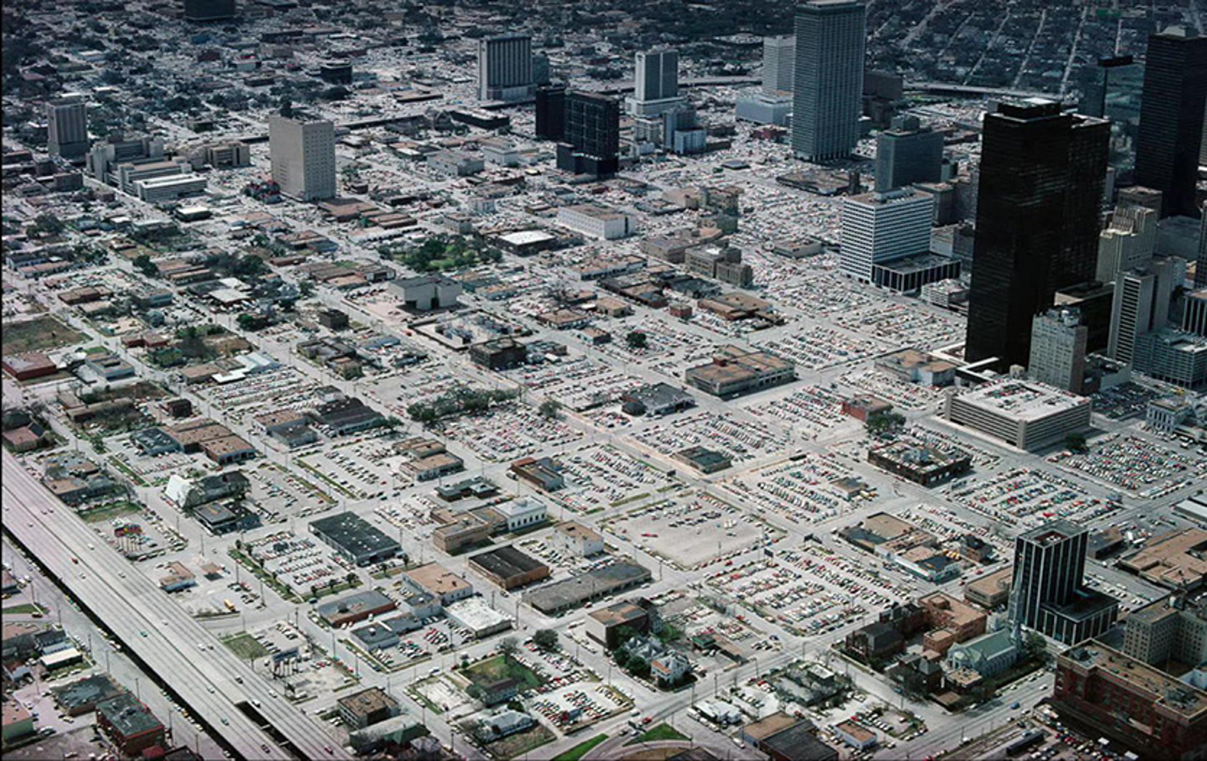 Aerial photo of a cityscape with numerous roads, buildings and parking areas densely packed throughout the urban environment.