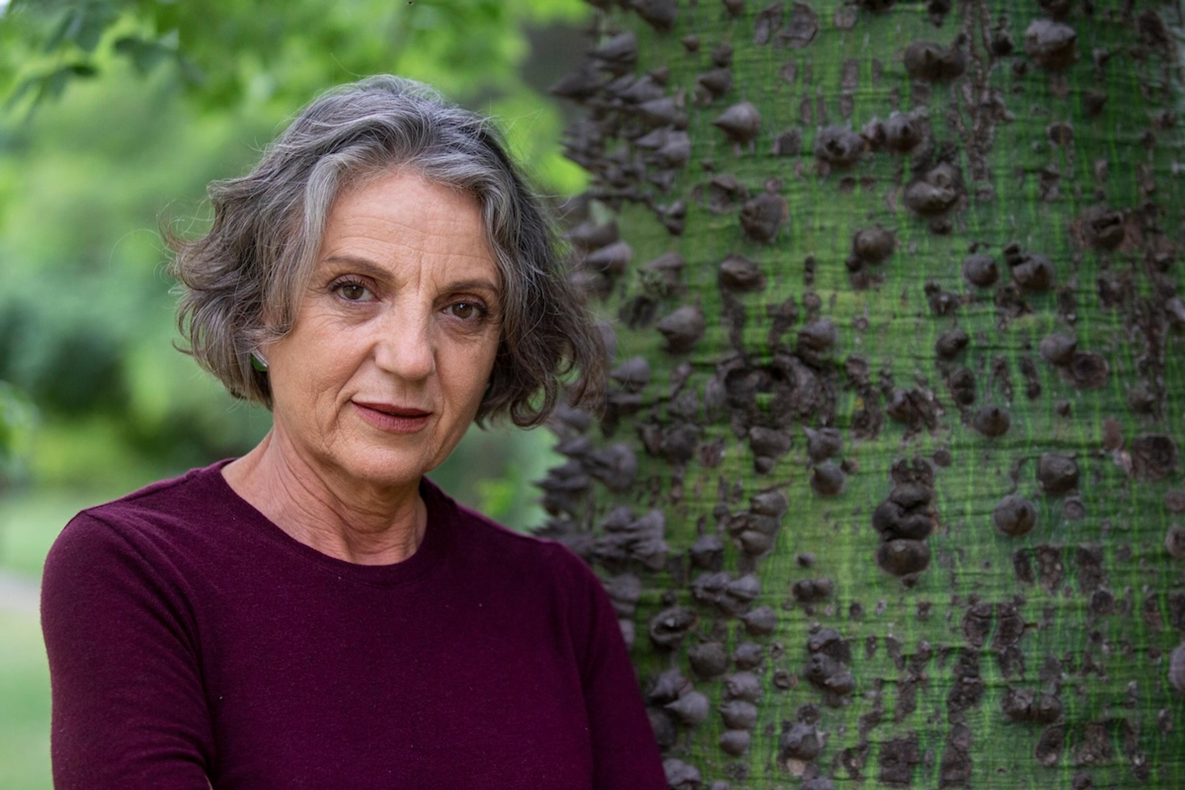 Photo of a woman leaning against a spiky green tree