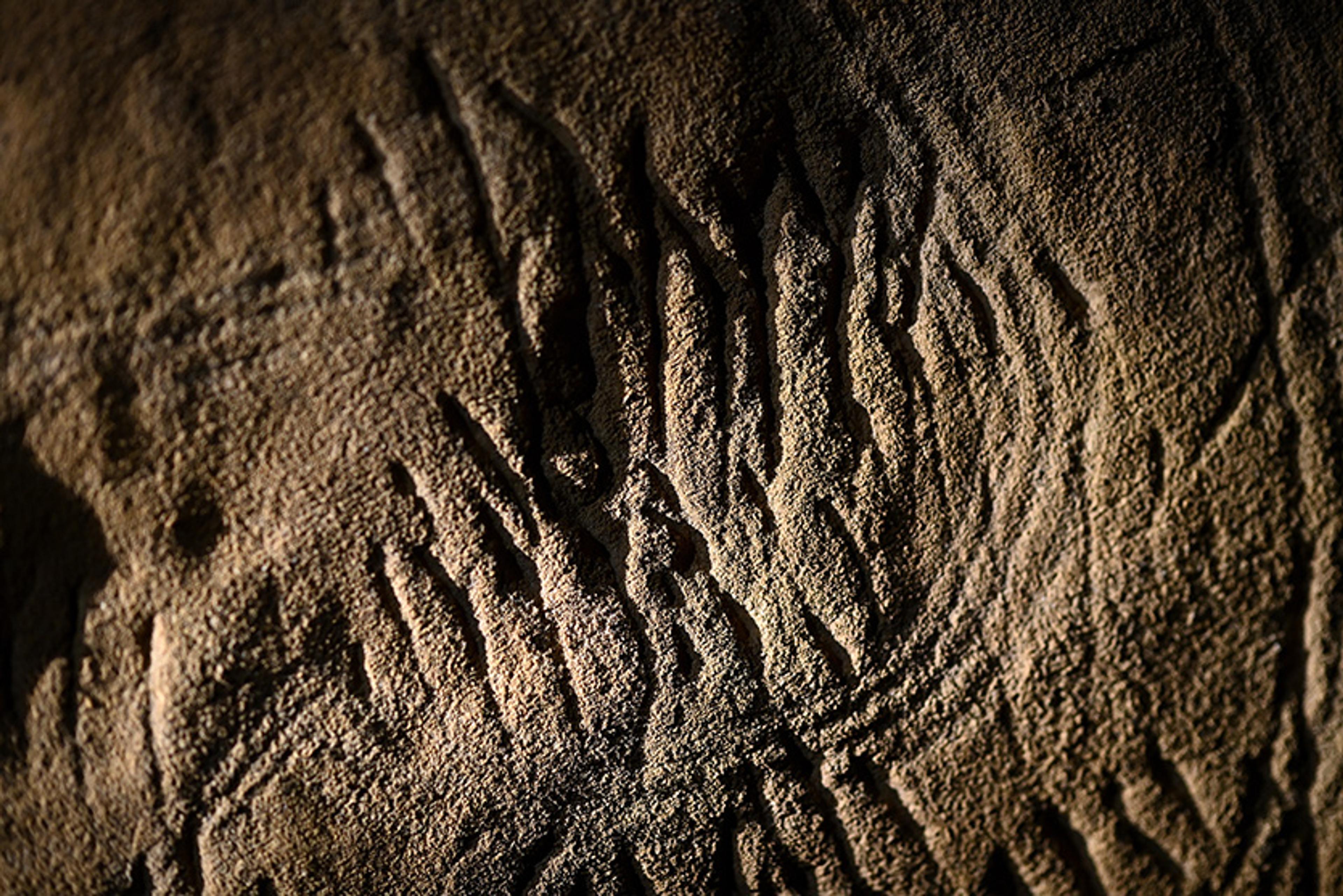 Ancient rock carvings with lines and patterns on a textured stone surface.