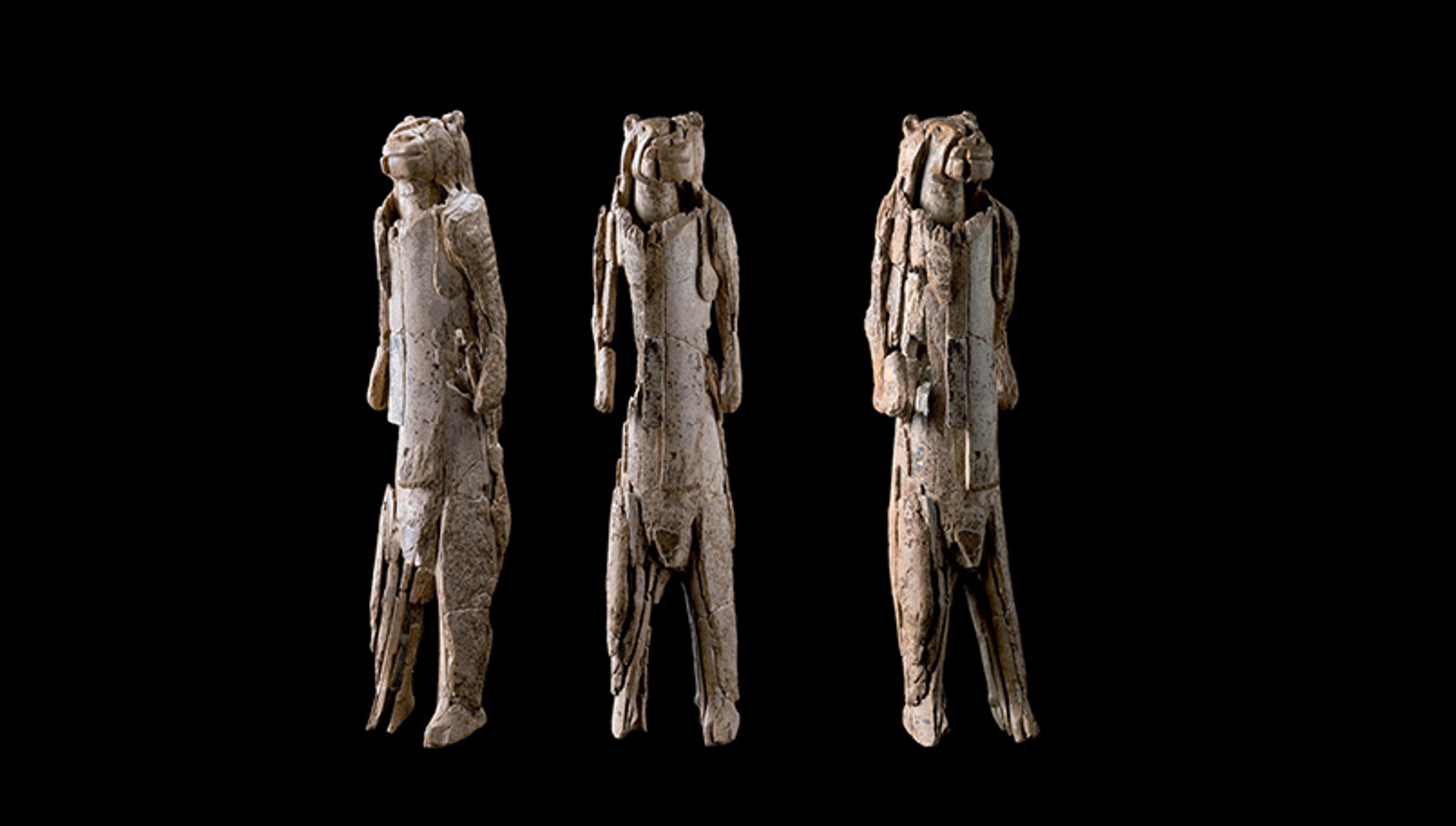 Ivory carvings of anthropomorphic figures with lion heads on a black background.