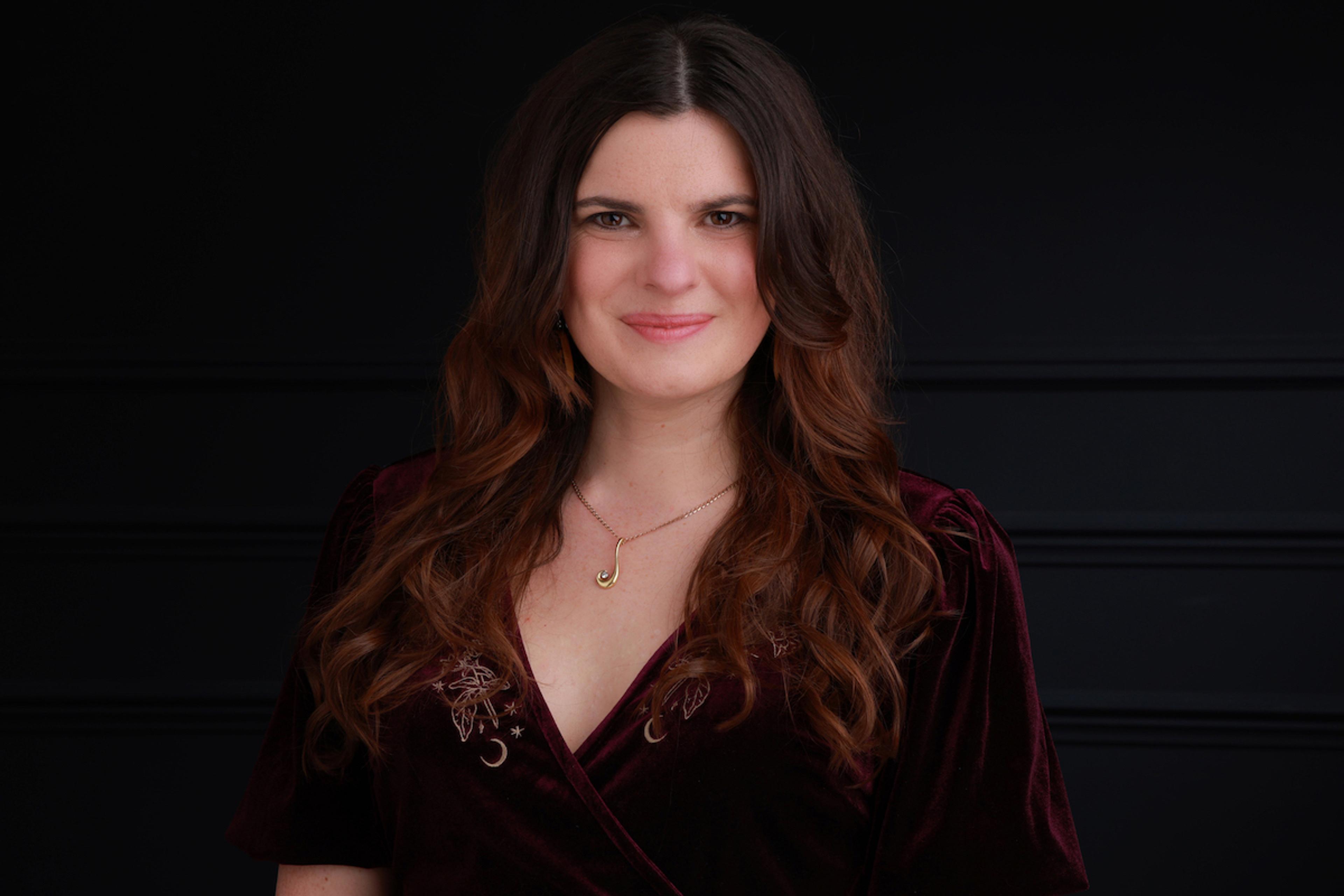 Photo of a woman with long brown hair against a dark background.