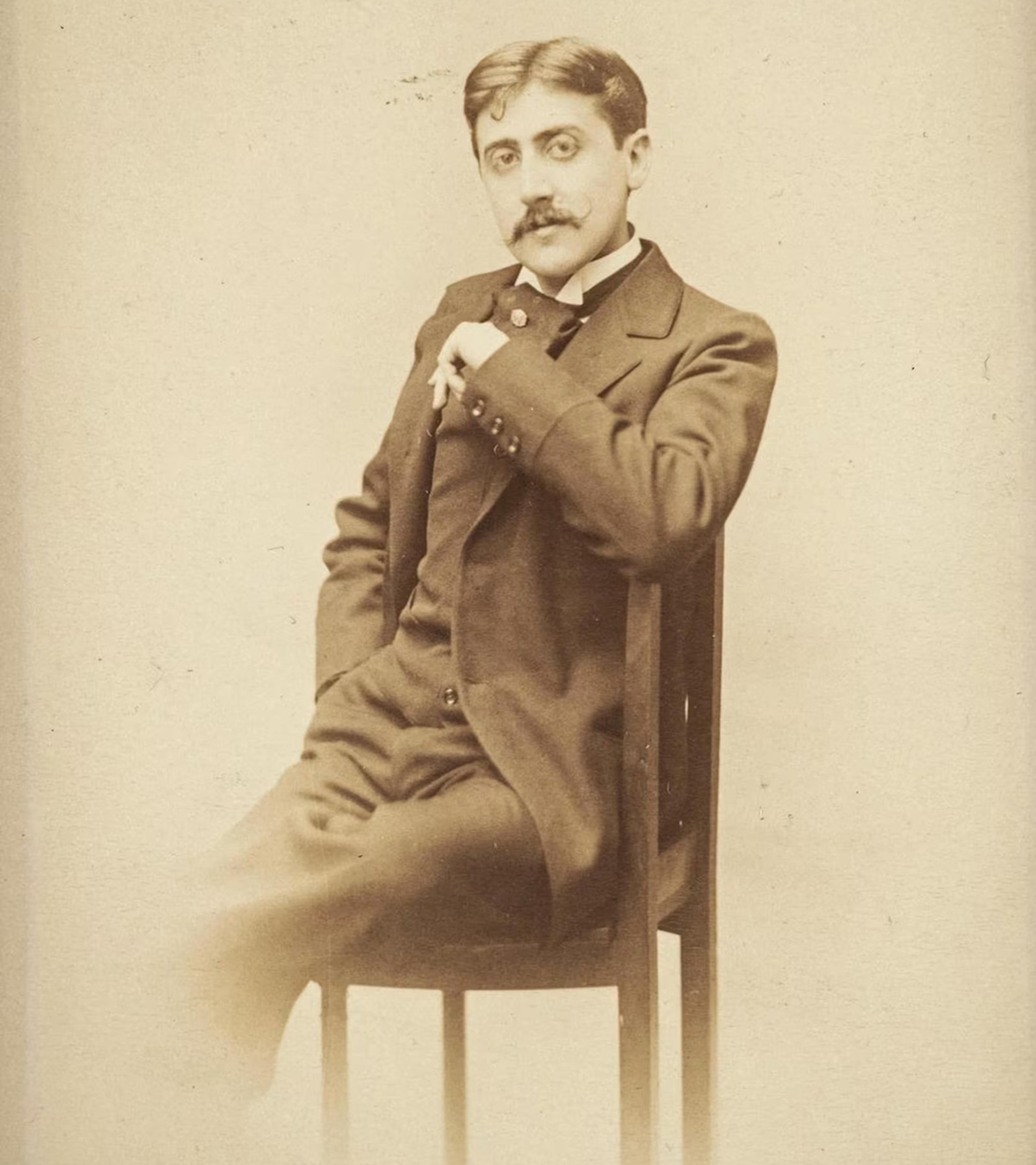Sepia-toned photo of a man with a moustache in a suit sitting on a chair, facing the camera in a relaxed pose.
