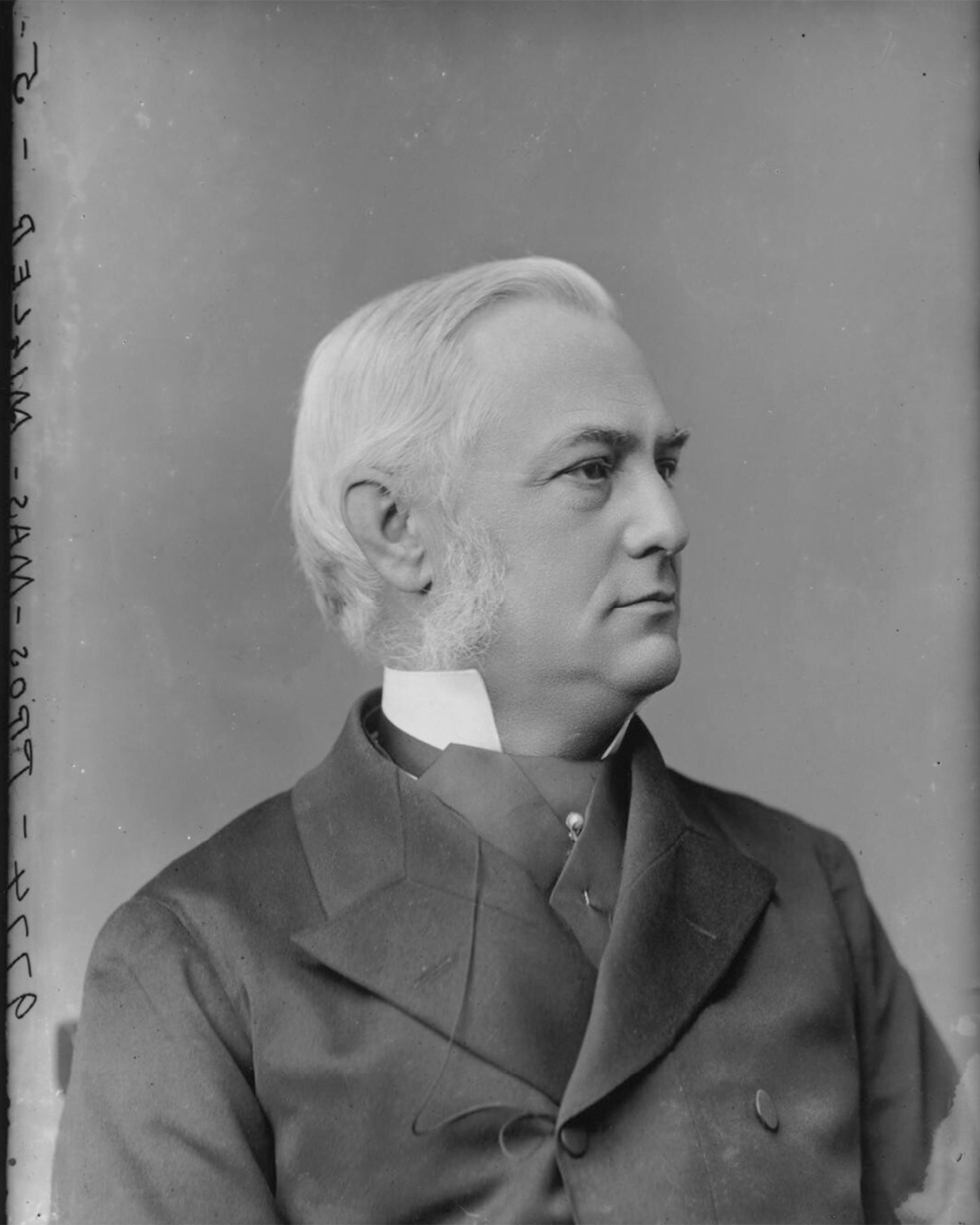 Black and white photo of an older man in a suit with sideburns, looking to the right against a plain background.
