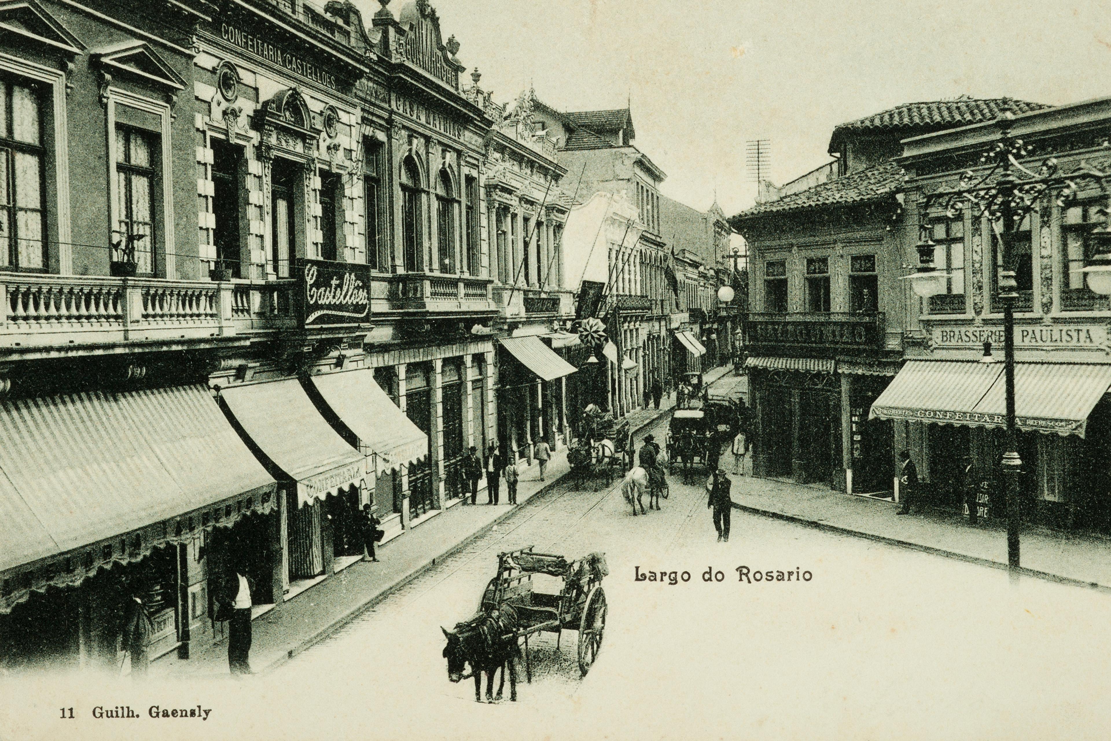 Vintage photo of Largo do Rosario street scene with horse-drawn carriages period architecture and pedestrians.