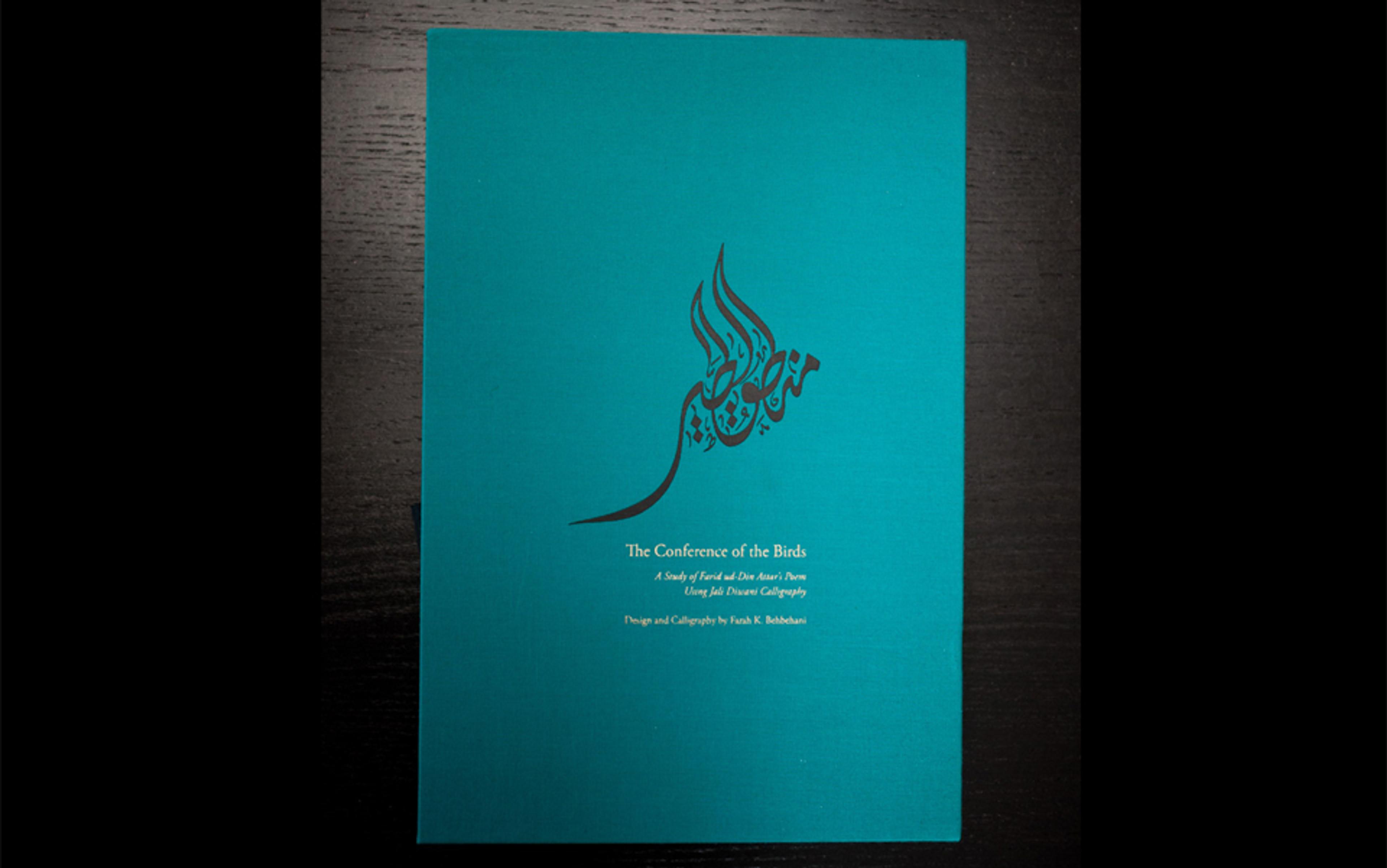 Photograph of a turquoise book cover titled “The Conference of the Birds” with Arabic calligraphy in the shape of a bird.
